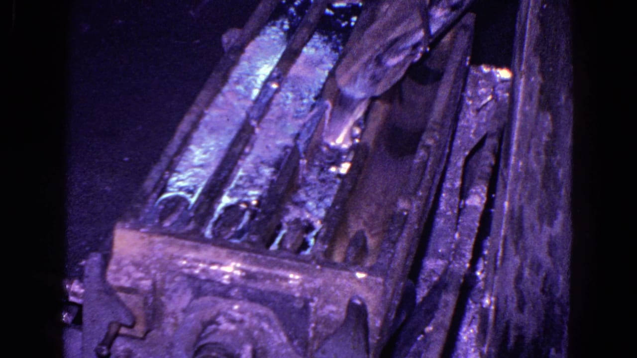 Worker's hand near a reflective metal mold or casting area.
