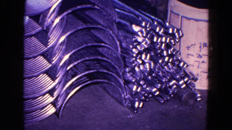 1967 Trenton factory frame showing stacked curved metal pieces beside a pile of smaller metal components on the floor.
