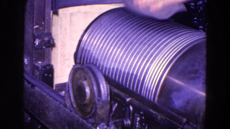 1967 industrial close-up showing the ribbed roller, circular side hardware, and dark structural parts of the machine during the process.