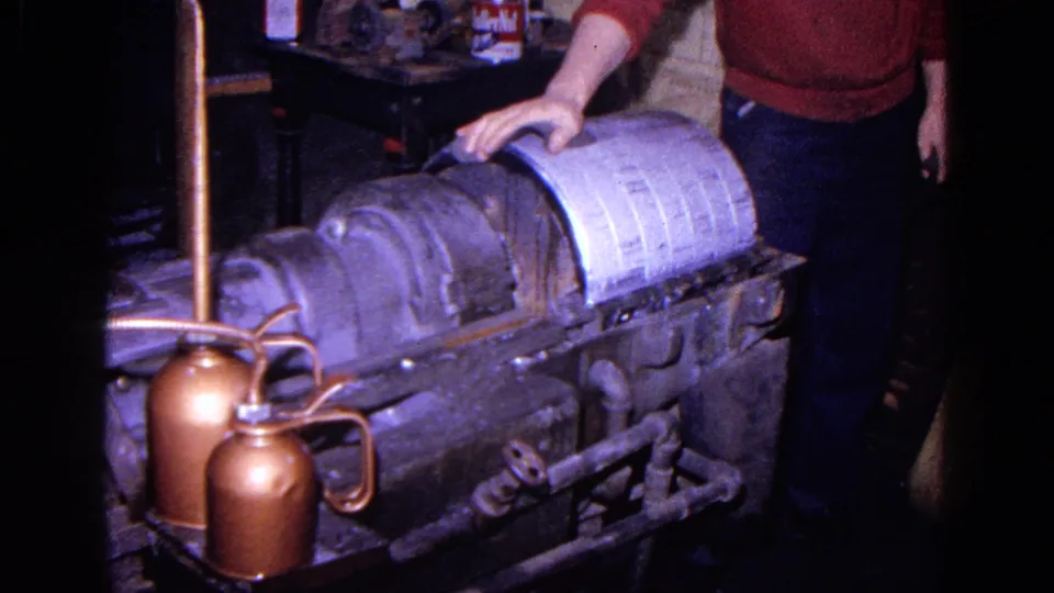 1967 Trenton frame showing a worker beside the linen processing machine, with copper oil cans and pipes visible in the workshop foreground.