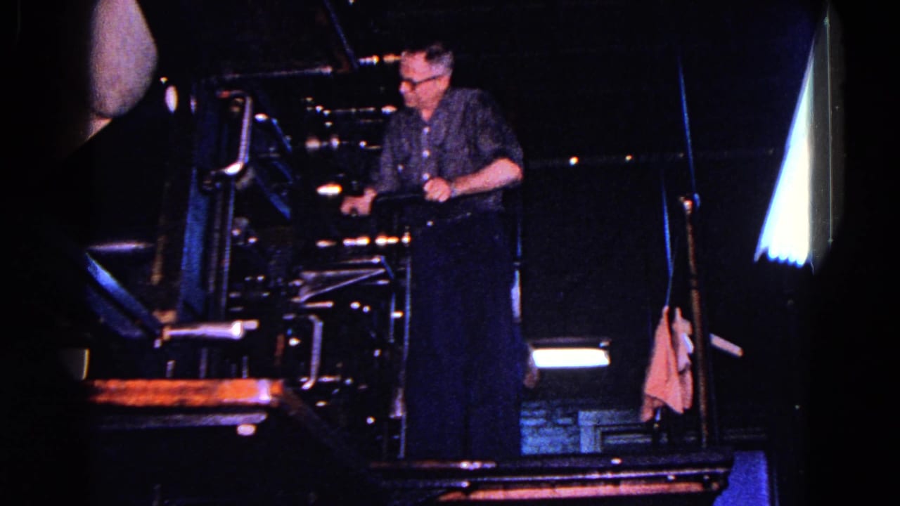 A man operates or adjusts a large industrial machine in a dark workshop or factory area, consistent with the 1967 Trenton metadata.