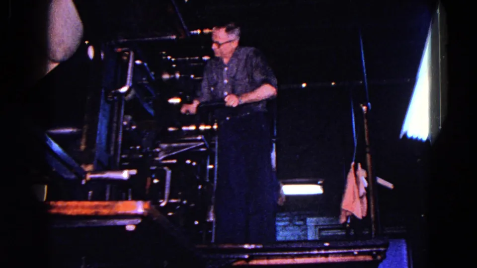 A man operates or adjusts a large industrial machine in a dark workshop or factory area, consistent with the 1967 Trenton metadata.