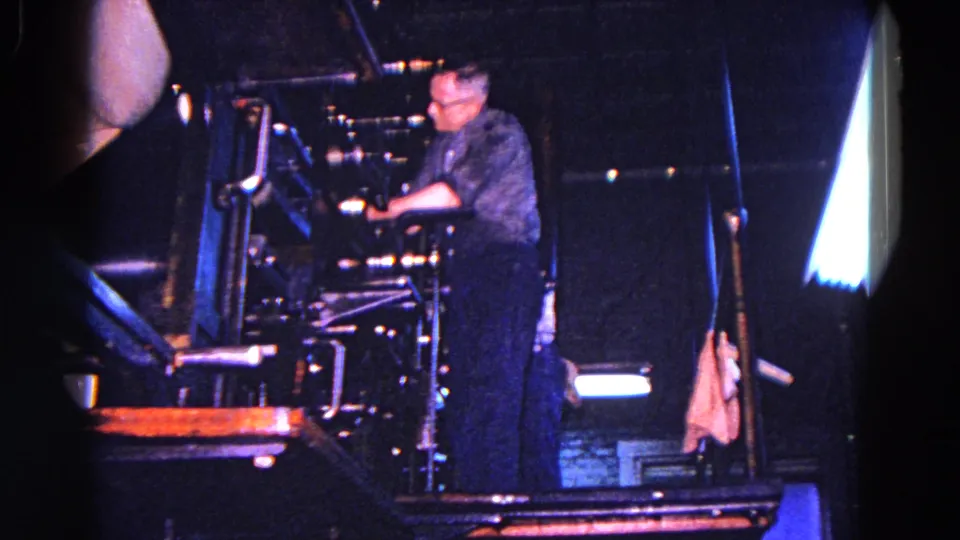 The Trenton factory scene shows the worker leaning into the press, with metal components and bright reflections around him.