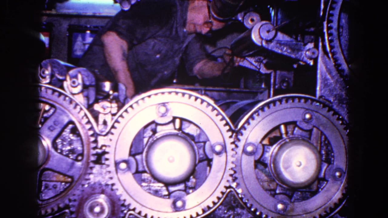 Large exposed machine gears with a worker partly visible behind them.