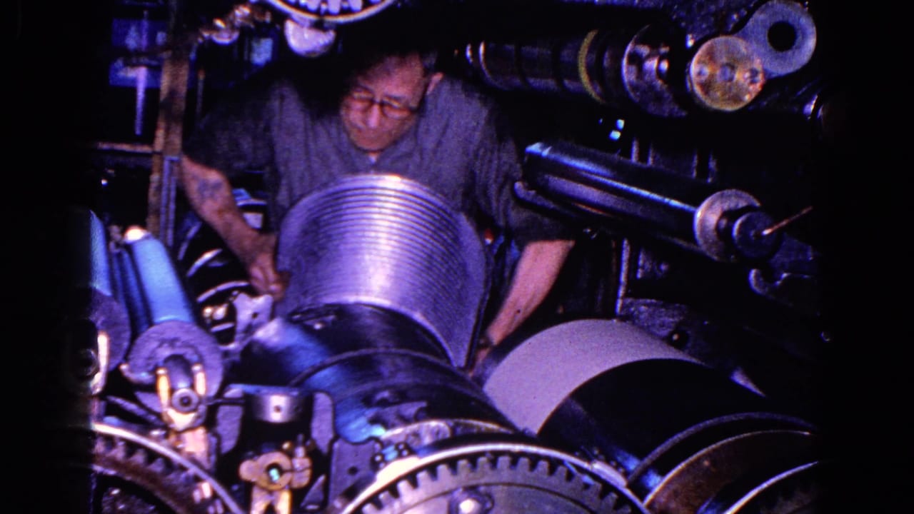 Worker handling a large ribbed cylinder inside industrial machinery.