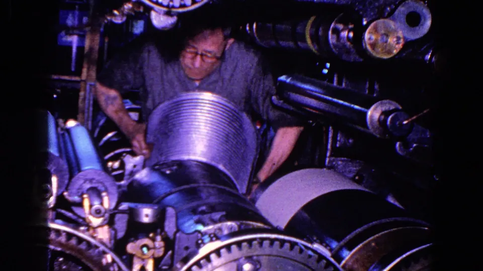A male worker in a dim Trenton factory appears to adjust a ribbed cylindrical machine component in 1967 footage.