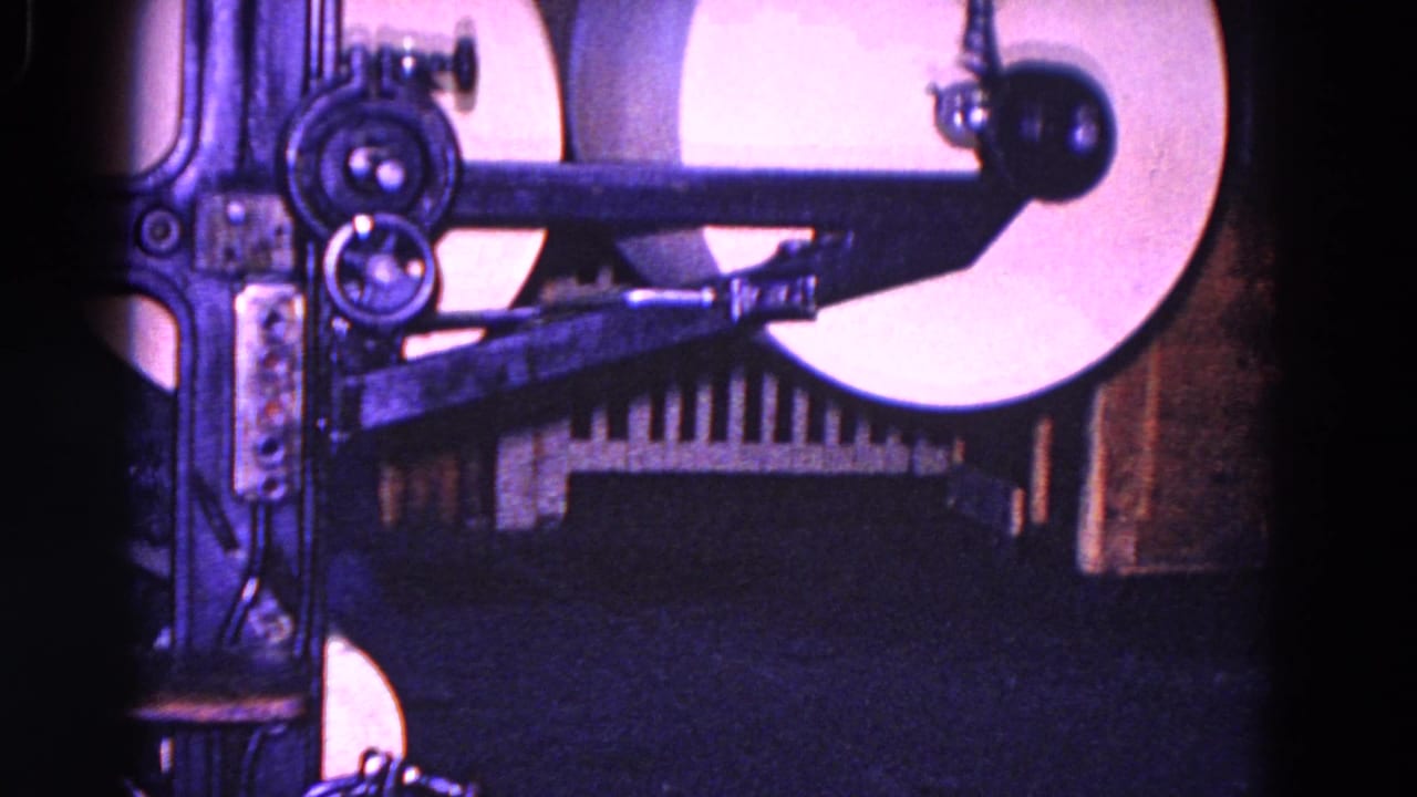 1967 Trenton 8mm frame showing white paper rolls and dark metal arms inside industrial paper-processing equipment.