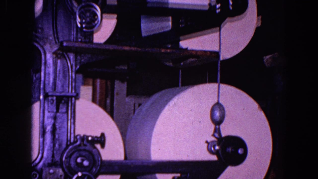 White paper rolls and black metal rollers fill the upper right frame.