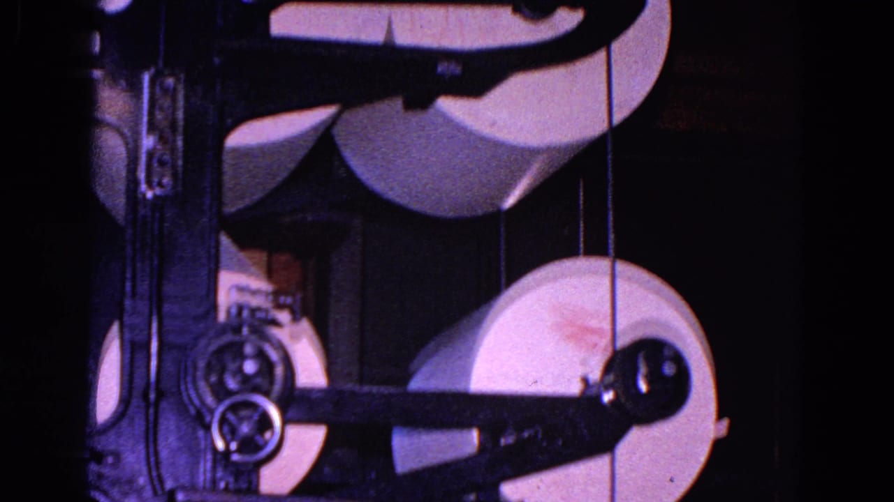 White paper rolls are stacked and routed through a metal paper-processing machine in the supplied 1967 Trenton clip.