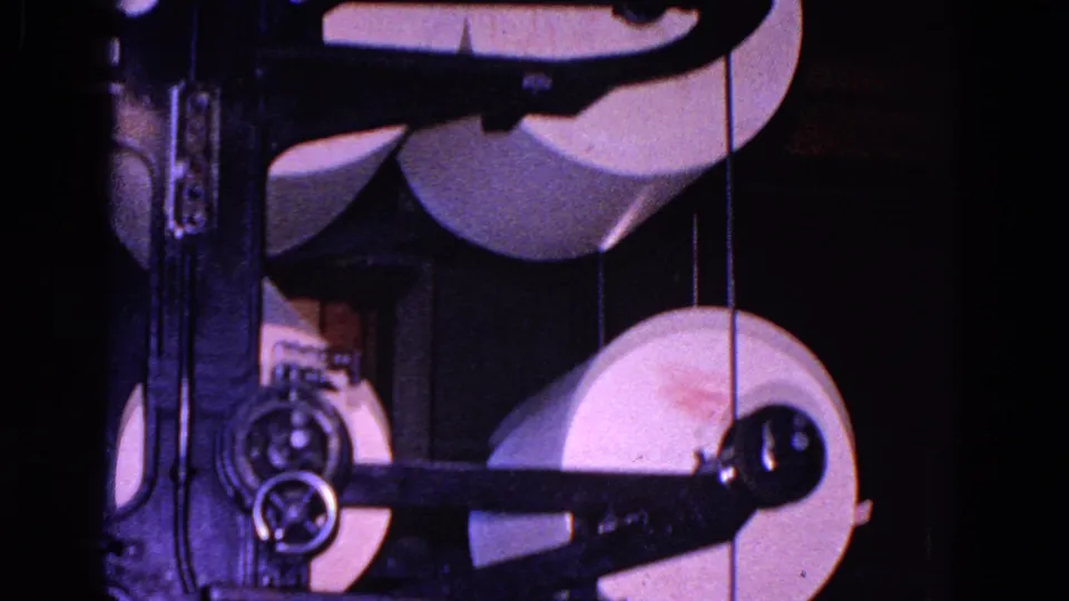 White paper rolls are stacked and routed through a metal paper-processing machine in the supplied 1967 Trenton clip.