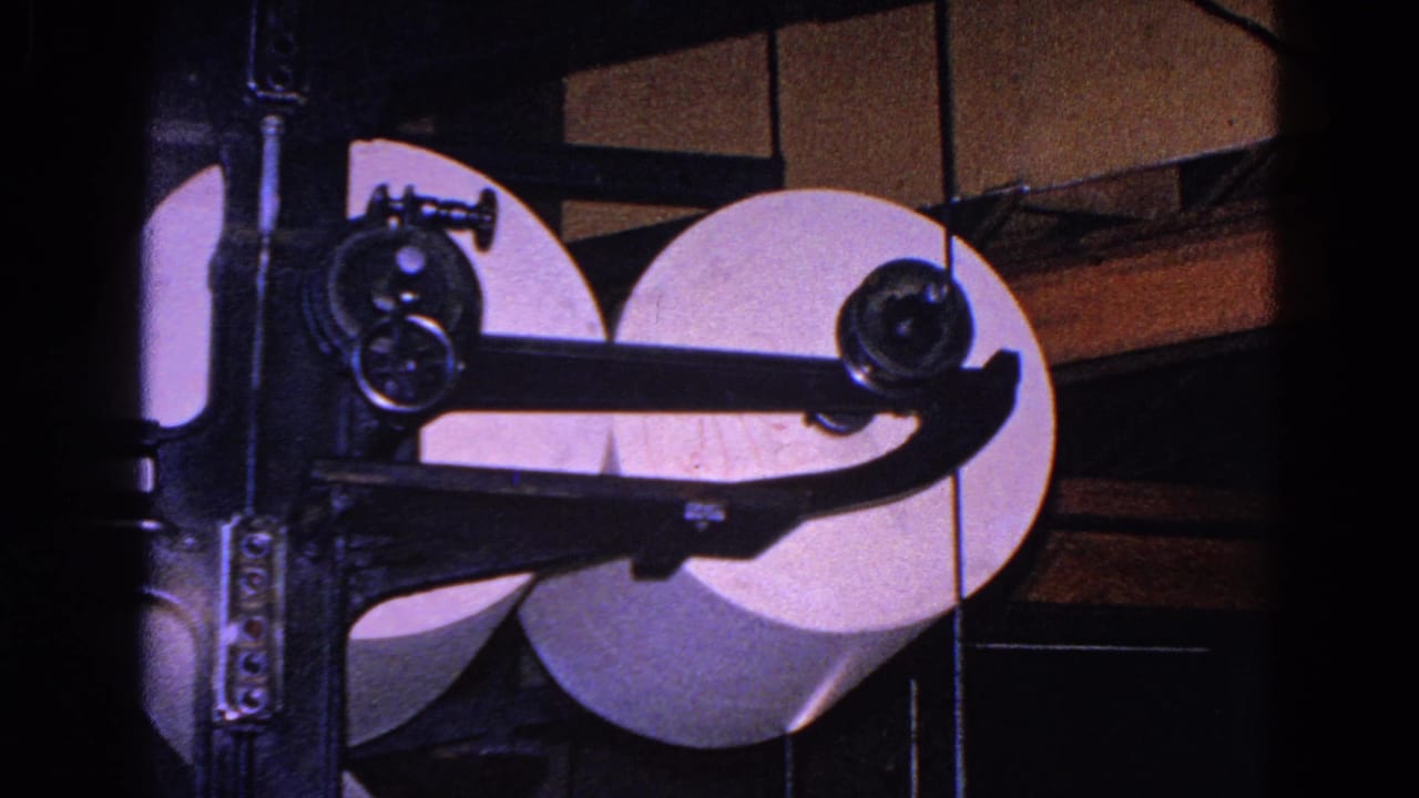 A later frame shows paper rolls, black roller arms, and boxy machine housing in the 1967 Trenton industrial scene.