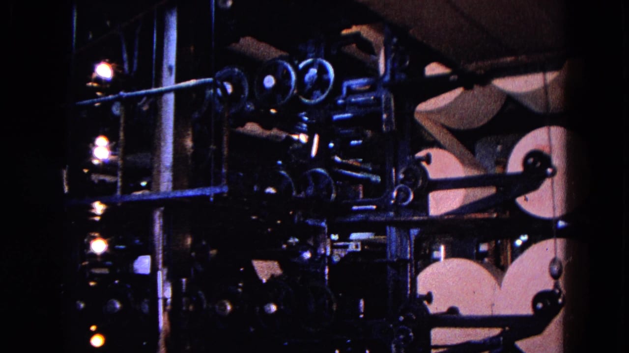 1967 Trenton industrial press view with paper rolls, rods, rollers, lamps, and a partially visible worker near the machinery.