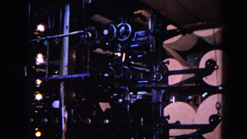 1967 Trenton industrial press view with paper rolls, rods, rollers, lamps, and a partially visible worker near the machinery.