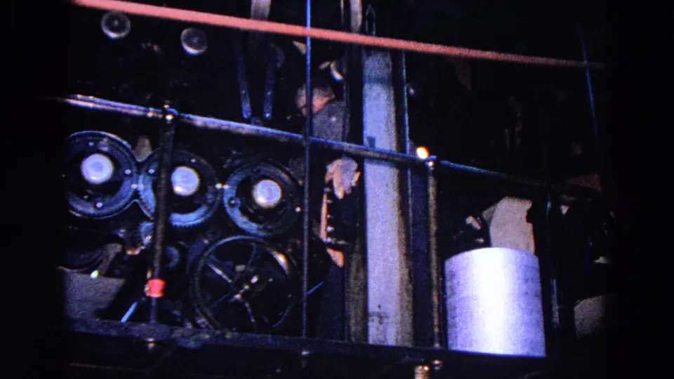 1967 Trenton factory view showing railings, pulleys, pipes, and a partially obscured worker near equipment.