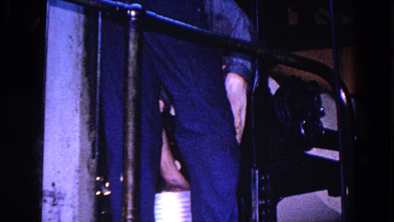 A worker in dark clothing stands close to machinery and railings inside the 1967 Trenton industrial interior.