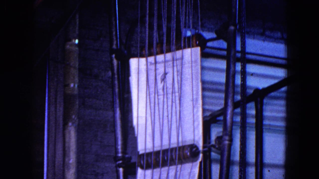A close view shows a pale stack of paper held or feeding through vertical rods and rollers on the printing machinery, with little human detail visible.