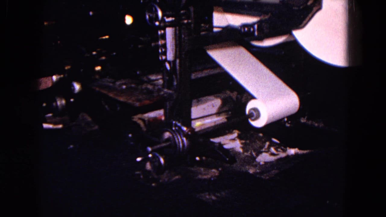 1967 Trenton 8mm frame showing dark newspaper press equipment and a white paper roll moving through the machine.