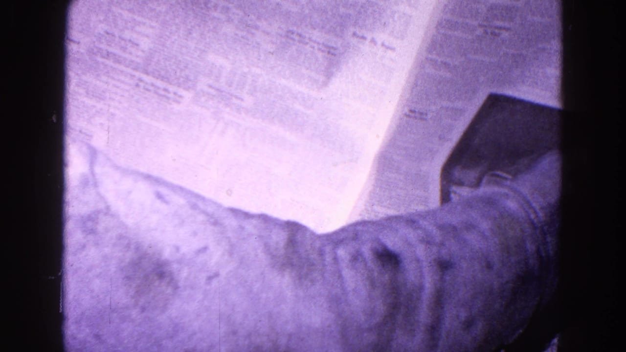 1967 Trenton 8mm frame with a close view of newspaper pages and an arm as printed output is handled.
