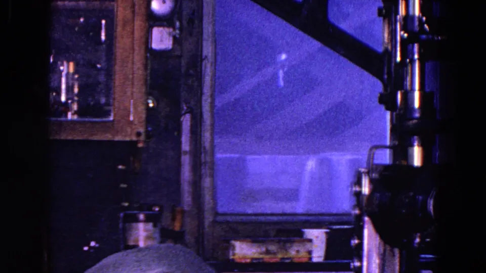 1967 Trenton interior frame showing a dark room with a window, cabinet, fixtures, and a newspaper edge in the foreground.