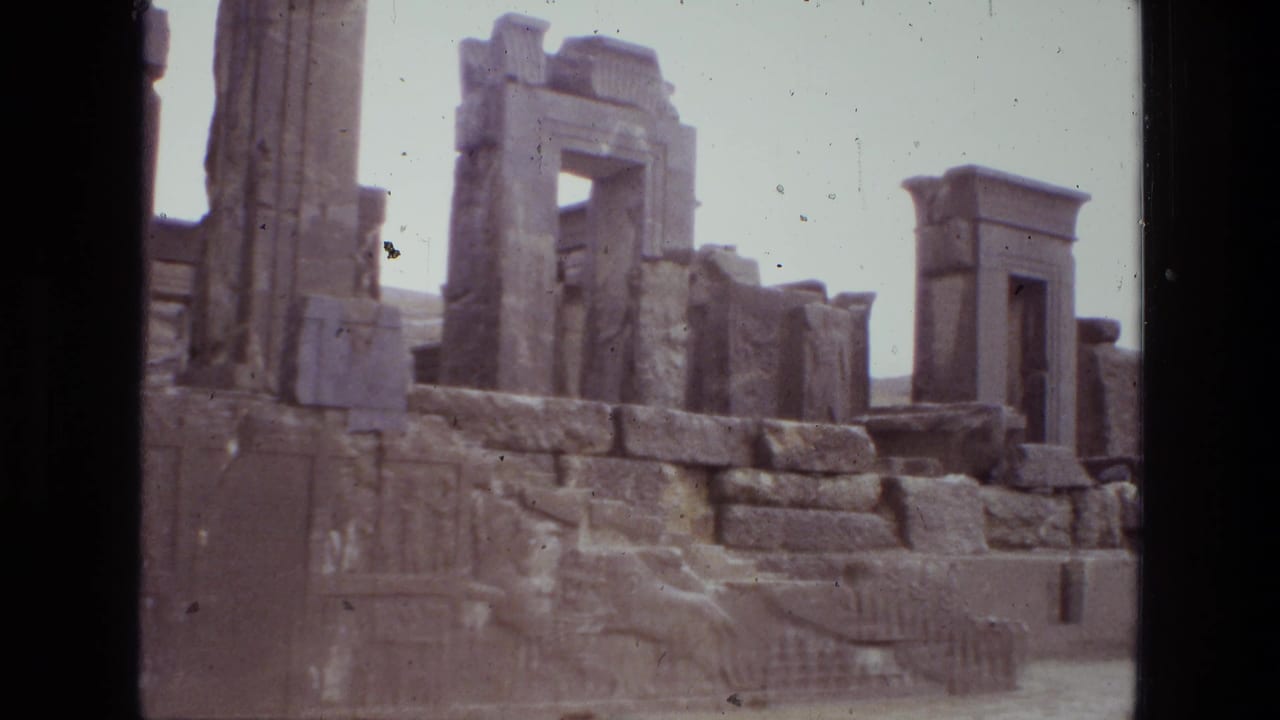 Ancient stone ruins with columns, carved reliefs, and a monumental opening under a pale sky.