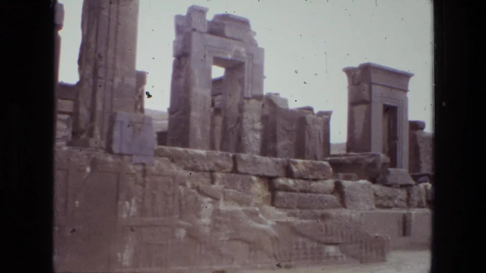 1972 8mm Iran footage showing weathered stone ruins, upright columns, carved reliefs, and a gateway-like opening in an arid setting.