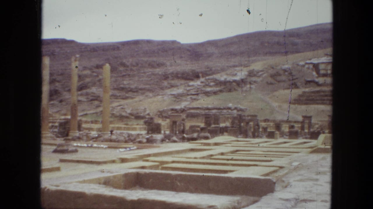 Persepolis ruins with stone foundations, columns, and hills behind them.
