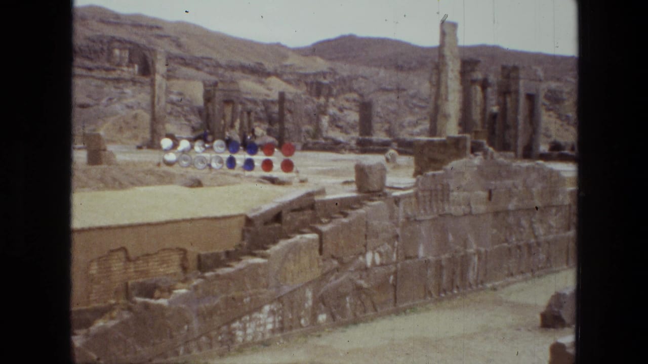 1972 Iran 8mm view of a ruin site with standing columns, low stone walls, sandy ground, hills, and red, blue, and white circular objects.