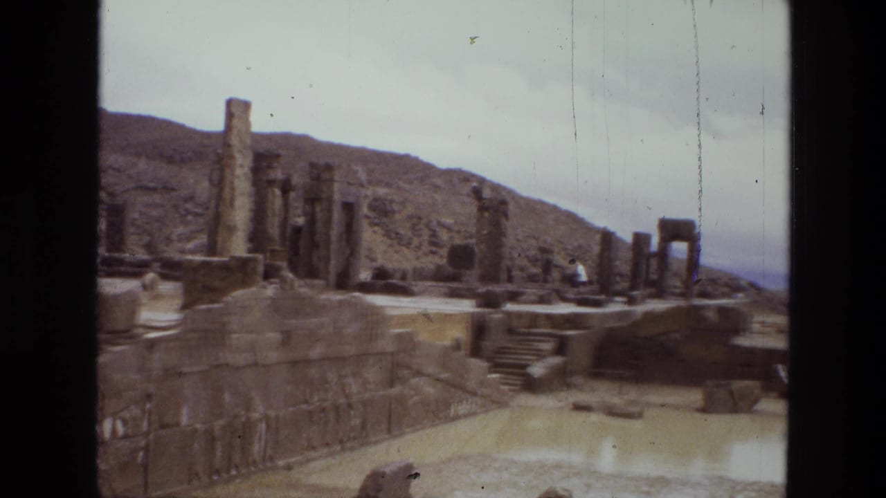 Stone columns and ruined platforms beside a muddy pool under a cloudy sky.