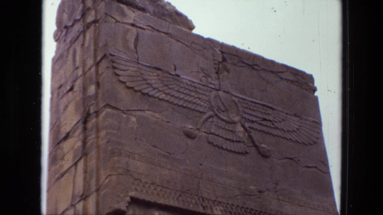 1972 Iran 8mm view of a stone monument face, centered on a raised winged carving and aged block seams.
