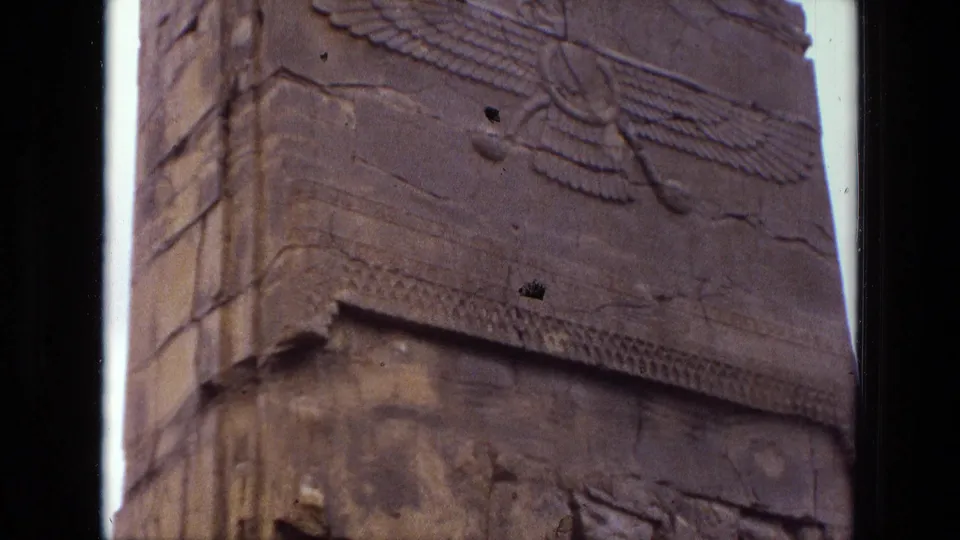 1972 Iran 8mm frame showing the lower ledge and winged carving on a weathered stone monument.