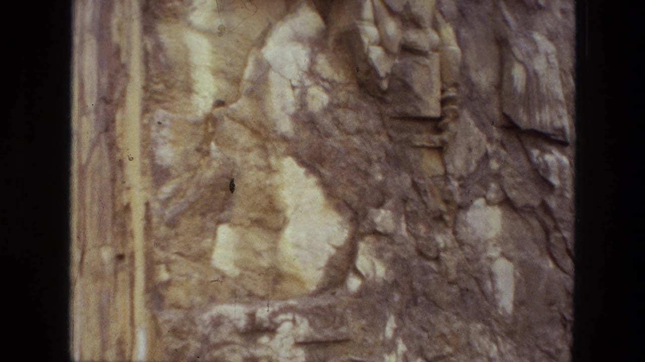 Close view of weathered carved stone beside a dark vertical gap.