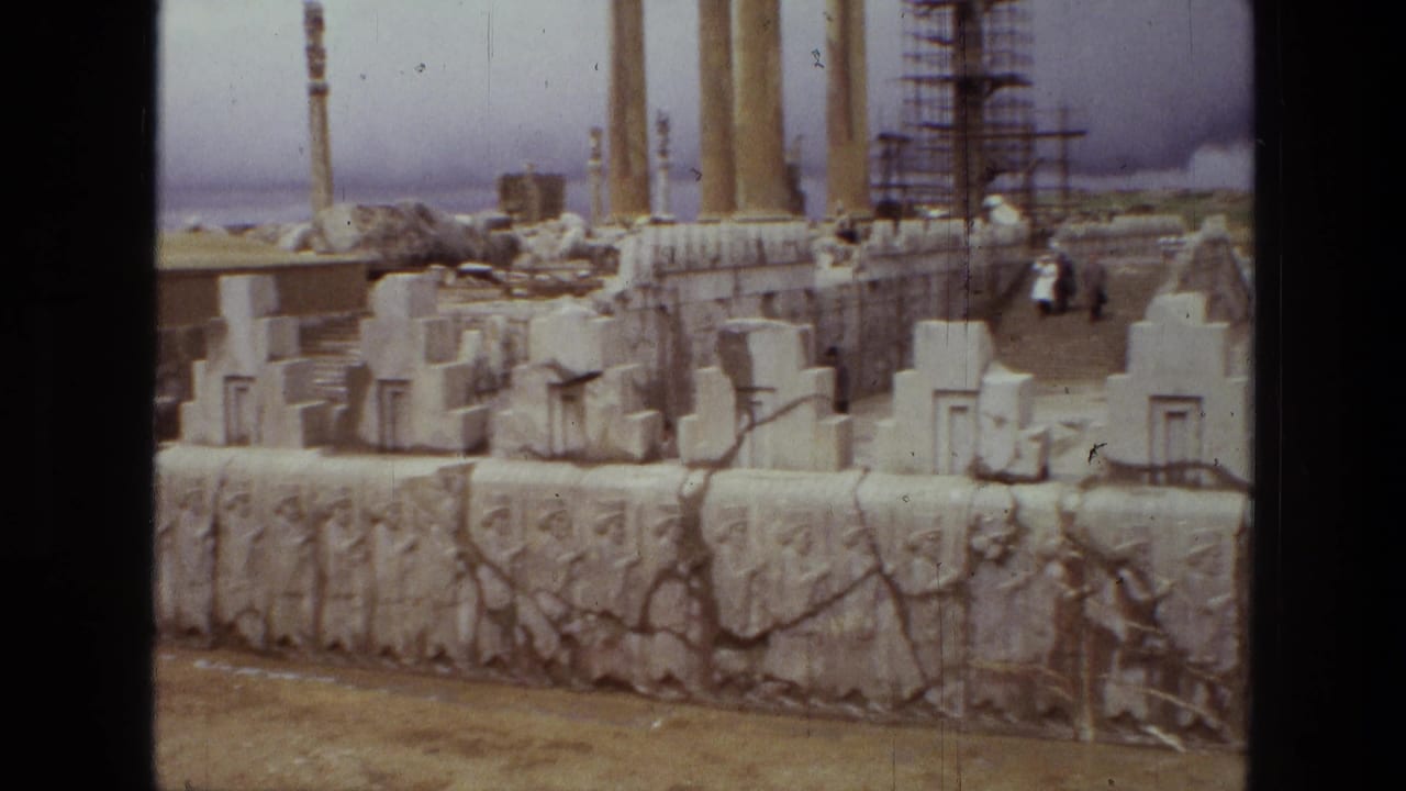 1972 8mm view of Persepolis in Iran, showing carved stone reliefs, block ruins, tall columns, and scaffolding in the background.