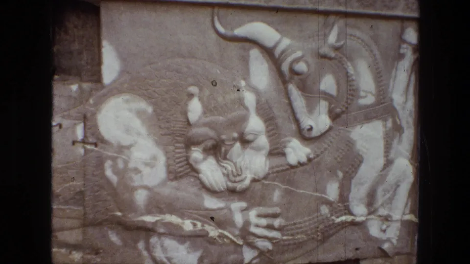 1972 Iran 8mm close view of carved stone figures beside a bull-like relief on a pale wall surface.