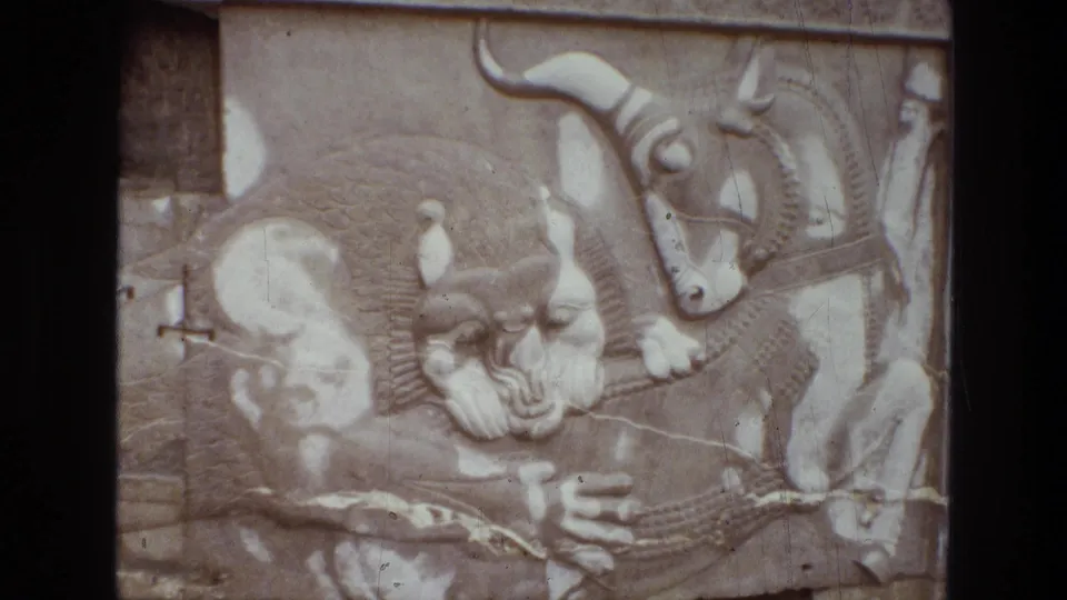 1972 Iran 8mm frame showing a close carved relief with human-form figures and a bull-like animal form.