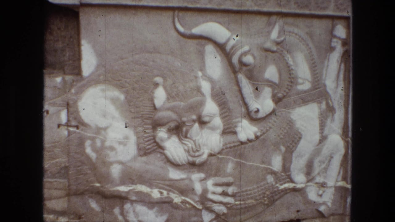 1972 Iran home-movie frame showing pale carved relief panels with horned animals, figures, and mythological forms in soft faded color.