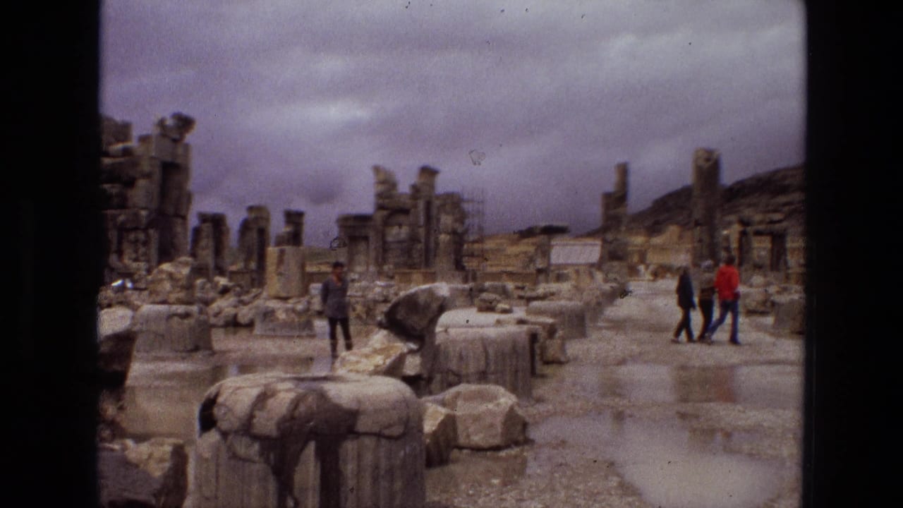 1972 Iran travel footage frame with tourists walking among ancient stone ruins, broken columns, rubble, and reflective rainwater.