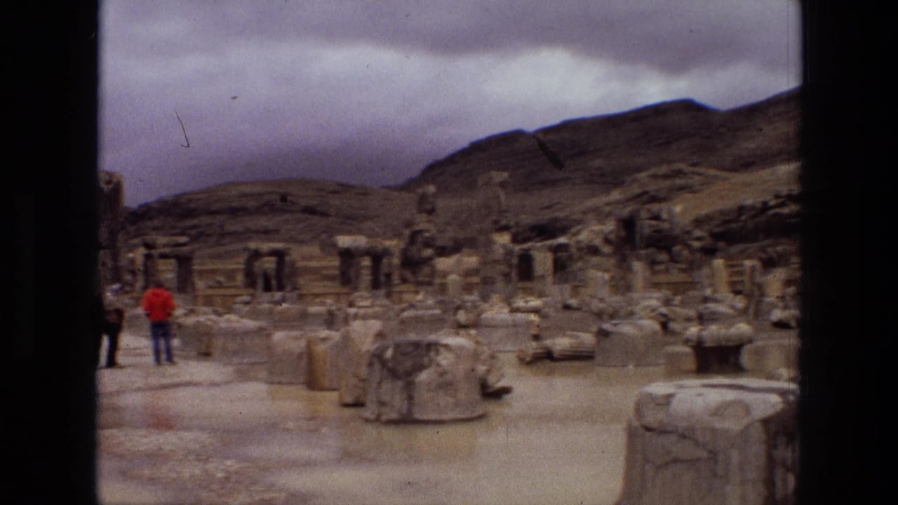 Visitors stand among stone ruins and broken blocks beneath a cloudy sky.