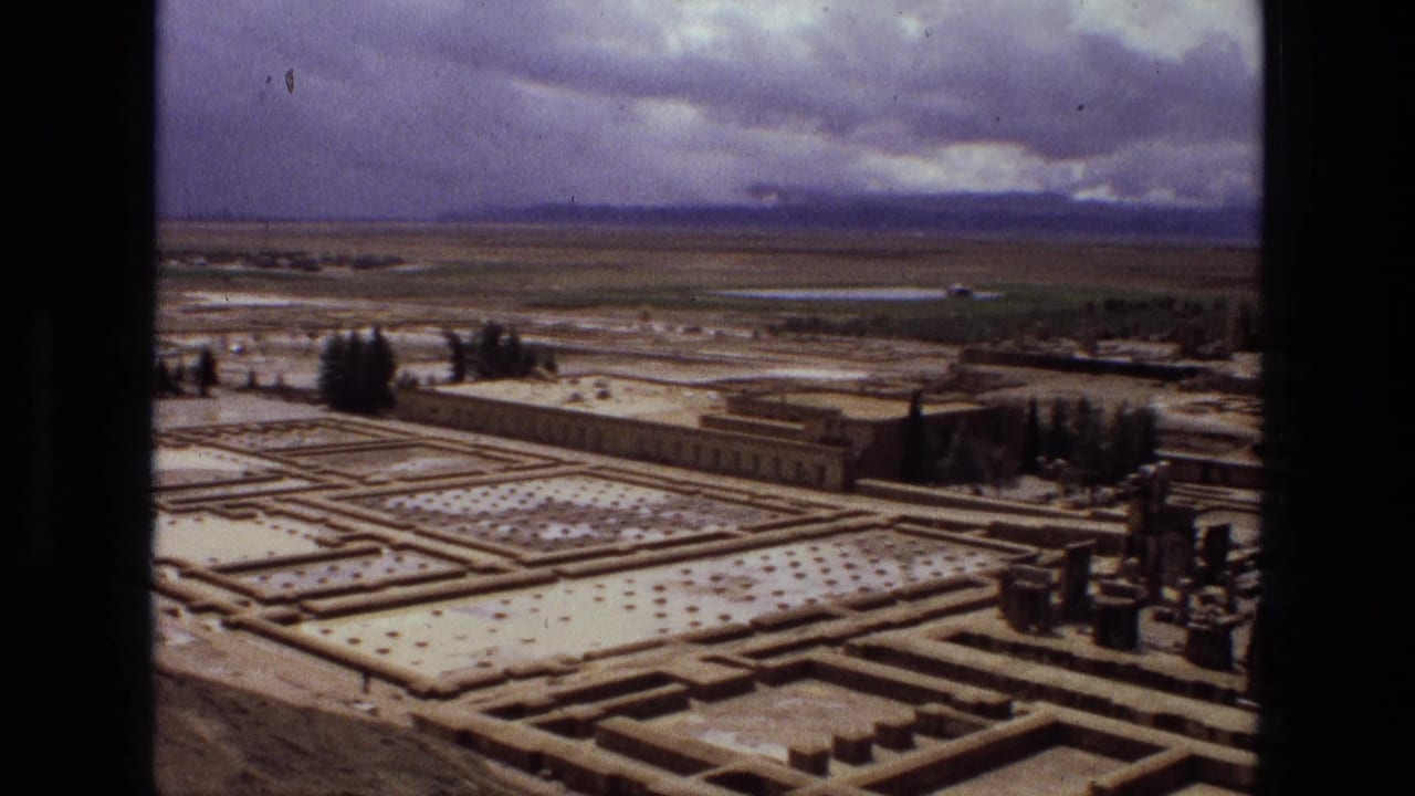 Elevated 1972 Iran view of a formal garden or ruin layout with rectangular paths, tree clusters, a long low building or wall, and distant horizon.
