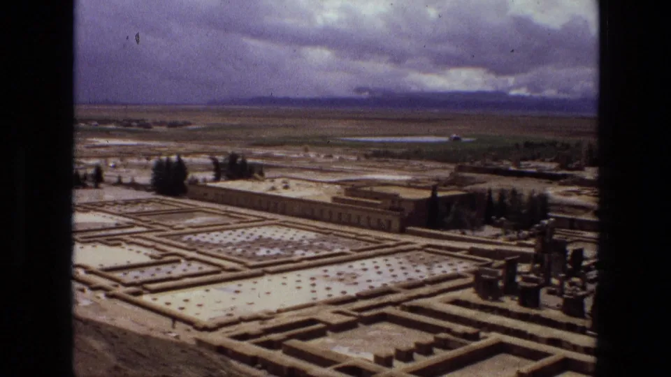 Elevated 1972 Iran view of a formal garden or ruin layout with rectangular paths, tree clusters, a long low building or wall, and distant horizon.