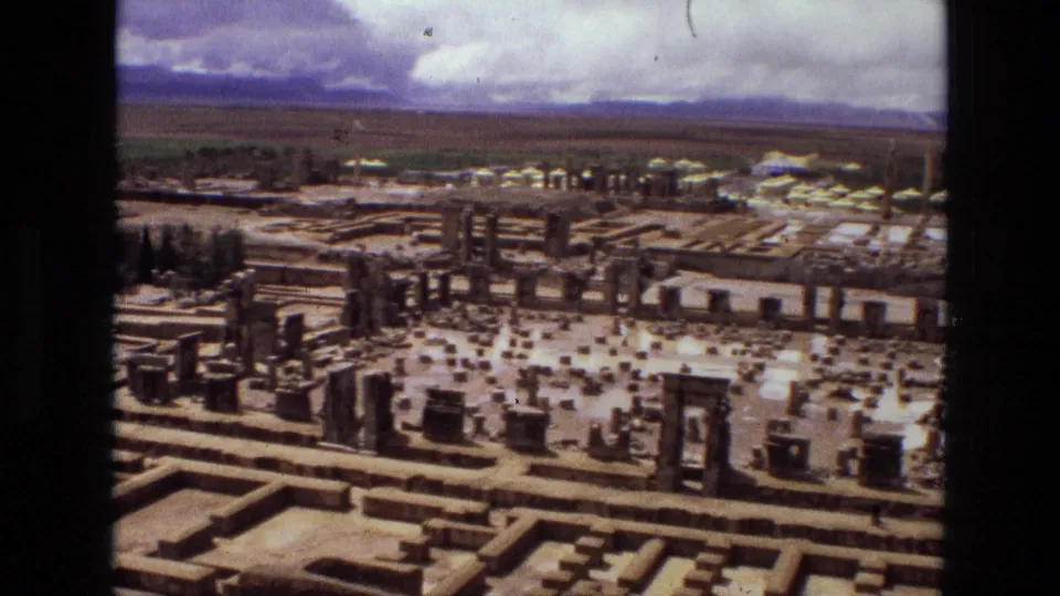 1972 8mm aerial view in Iran, likely Persepolis, showing ancient stone foundations, columns, and distant mountains.