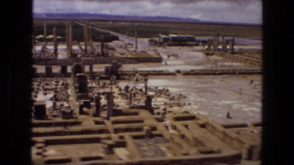 1972 Iran 8mm aerial footage, likely Persepolis, with ancient foundations, columns, open visitor areas, and mountains beyond.