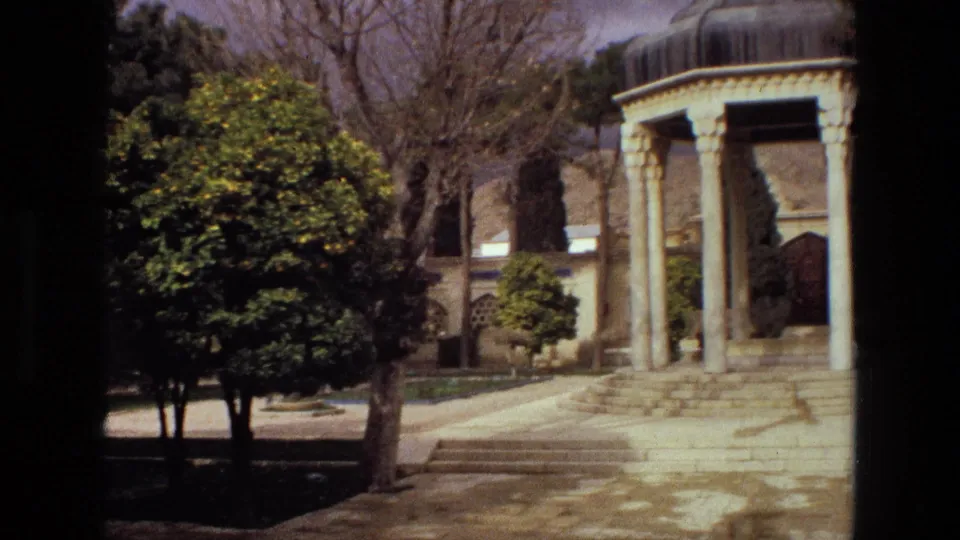 1972 Iran frame showing the pavilion off to the right, partly cropped by the camera, with trees and shrubs in the foreground.