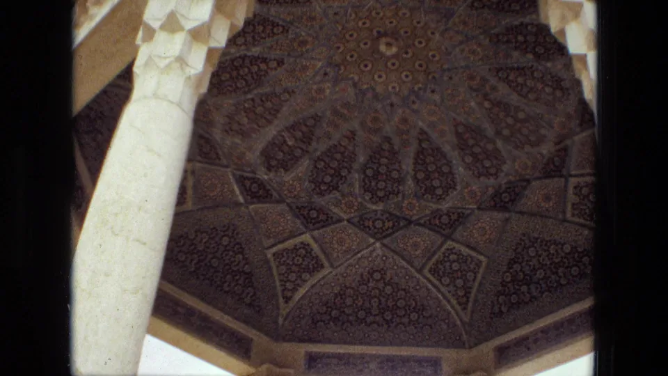 1972 Iran home-movie frame looking up at a patterned Islamic-style dome supported by pale carved columns.