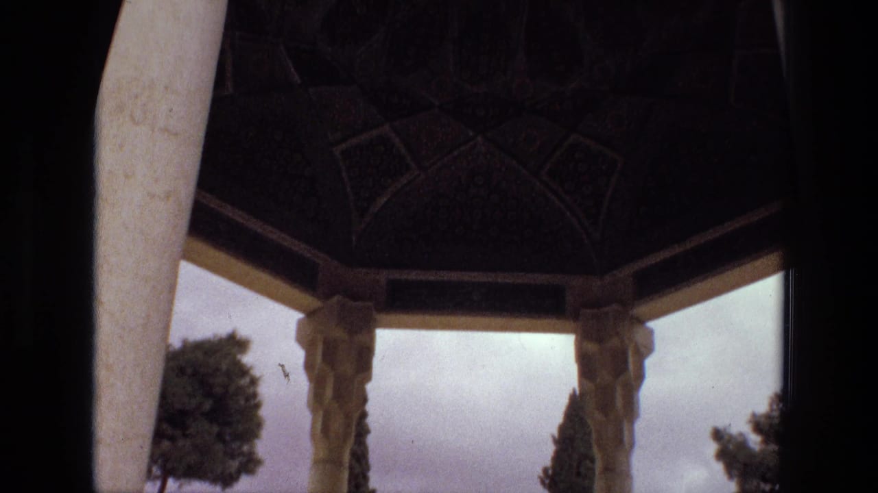 View from inside a pavilion toward columns, trees, and cloudy sky.
