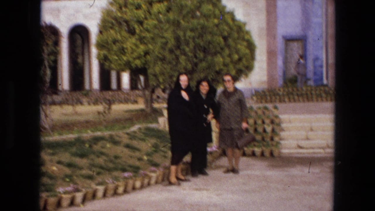 The three women appear farther from the camera in an Iranian garden, with steps, planted pots, trees, and a building entrance visible.
