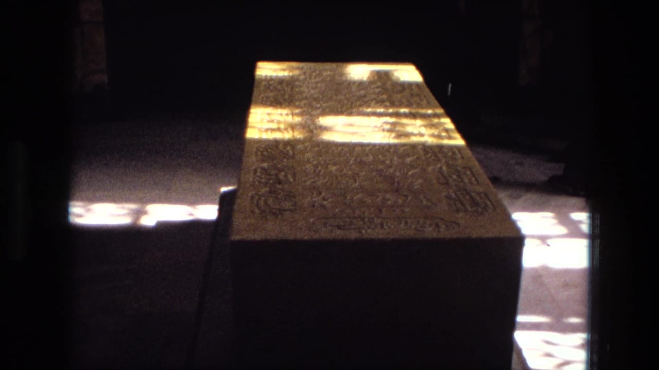 1972 Iran home-movie frame showing a stone tomb inside a dim historic interior, with bright window light across the floor.