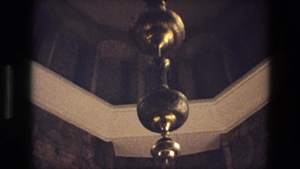 1972 Iran 8mm frame tilting toward a brass chandelier suspended beneath an arched interior ceiling.