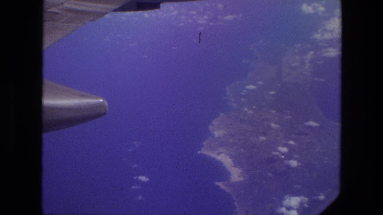 1972 Iran aerial view from a passenger window, with aircraft wing above coastline, ocean, and scattered clouds.