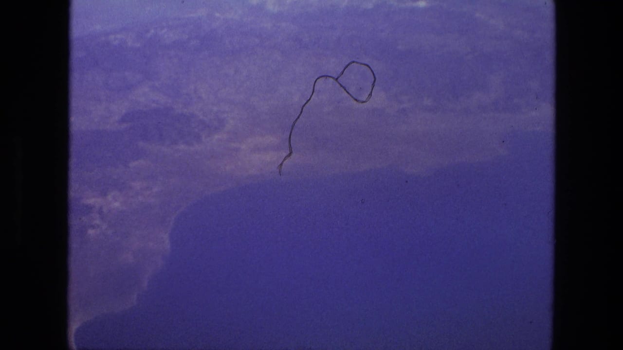 Blue-tinted film frame with aircraft-window view and visible film scratch.