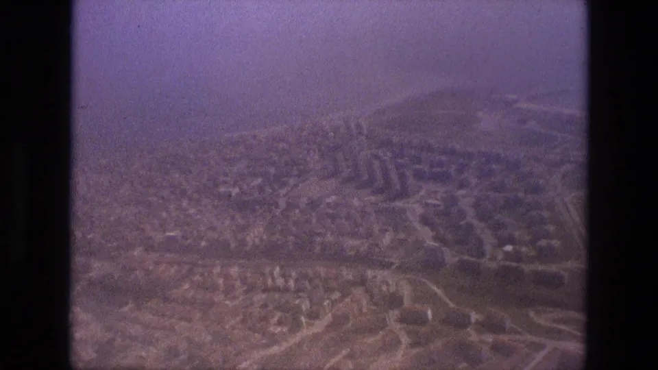 1972 Iran home-movie aerial view of an urban area with roads, small buildings, and distant hills.